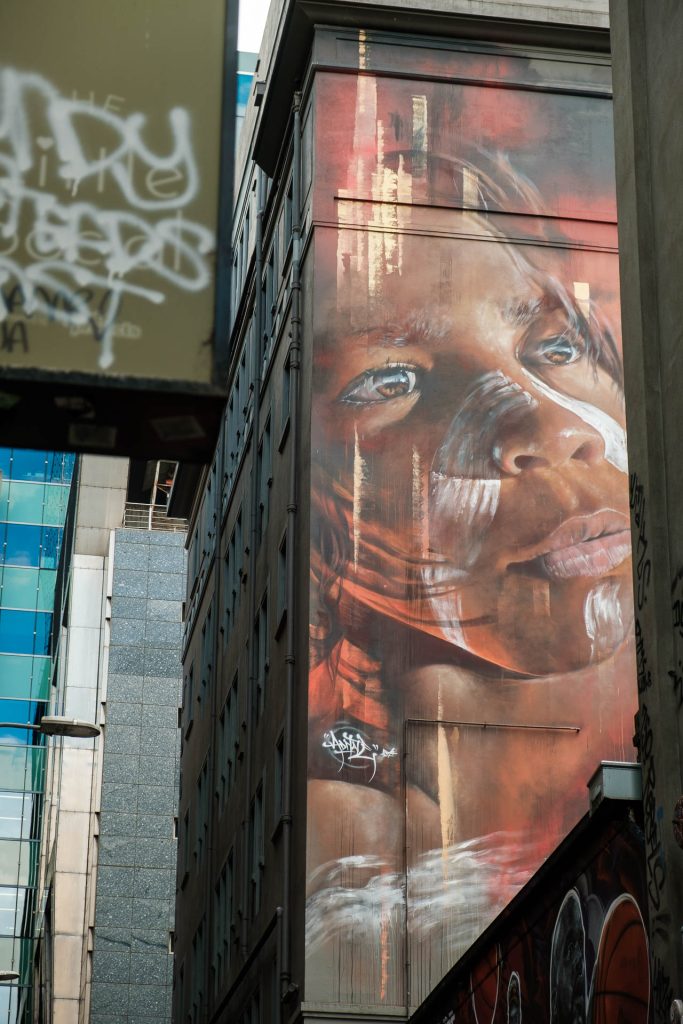 The view of Adnate's portrait of a young Aboriginal boy, seen from Hosier Lane.